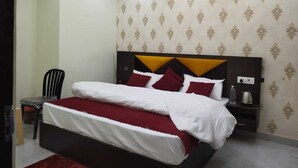 Ein ordentlich eingerichtetes Hotelzimmer mit einem Bett, einem Nachttisch und einem Sessel.