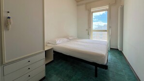 A bedroom with a bed, a dresser, and a window with a view of buildings. - 2 Sea View Penthouse with Large Balcony (Bellaria-Igea Marina)