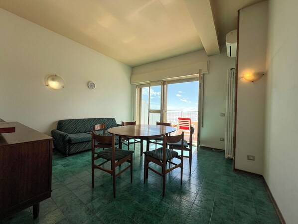 A room with a dining table and chairs, a sofa, a clock, and a window with a view of the sky. - 2 Sea View Penthouse with Large Balcony (Bellaria-Igea Marina)