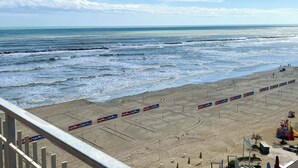 A beach with waves, a sandy area with advertisements, and a clear sky. - 2 Sea View Penthouse with Large Balcony (Bellaria-Igea Marina)