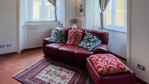 A cozy living room with a red leather sofa, patterned cushions, a red and white rug, and a wooden ceiling. - Inn Pantheon home lovely apartment 50 meters from the Pantheon (Roma)
