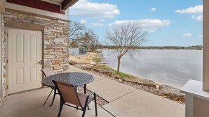 Une terrasse avec une table et des chaises, un mur en pierre et une vue sur un lac.