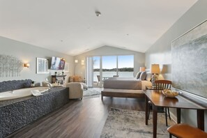 Ein geräumiges Zimmer mit großem Fenster, einer Badewanne, einem Sofa und einem Essbereich.