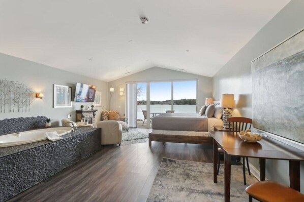 A spacious room with a large window, a bathtub, a sofa, and a dining area.