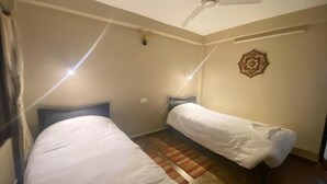 A room with two beds, a ceiling fan, and a decorative wall piece.