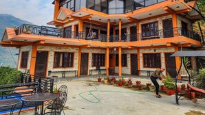 A multi-story building with balconies, a sign reading "Purna Yoga," and outdoor seating with potted plants.