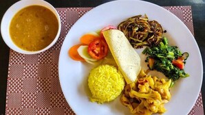 A plate of food with rice, vegetables, and a bowl of soup.
