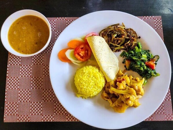 Une assiette de nourriture composée de riz, de légumes et d’un bol de soupe.