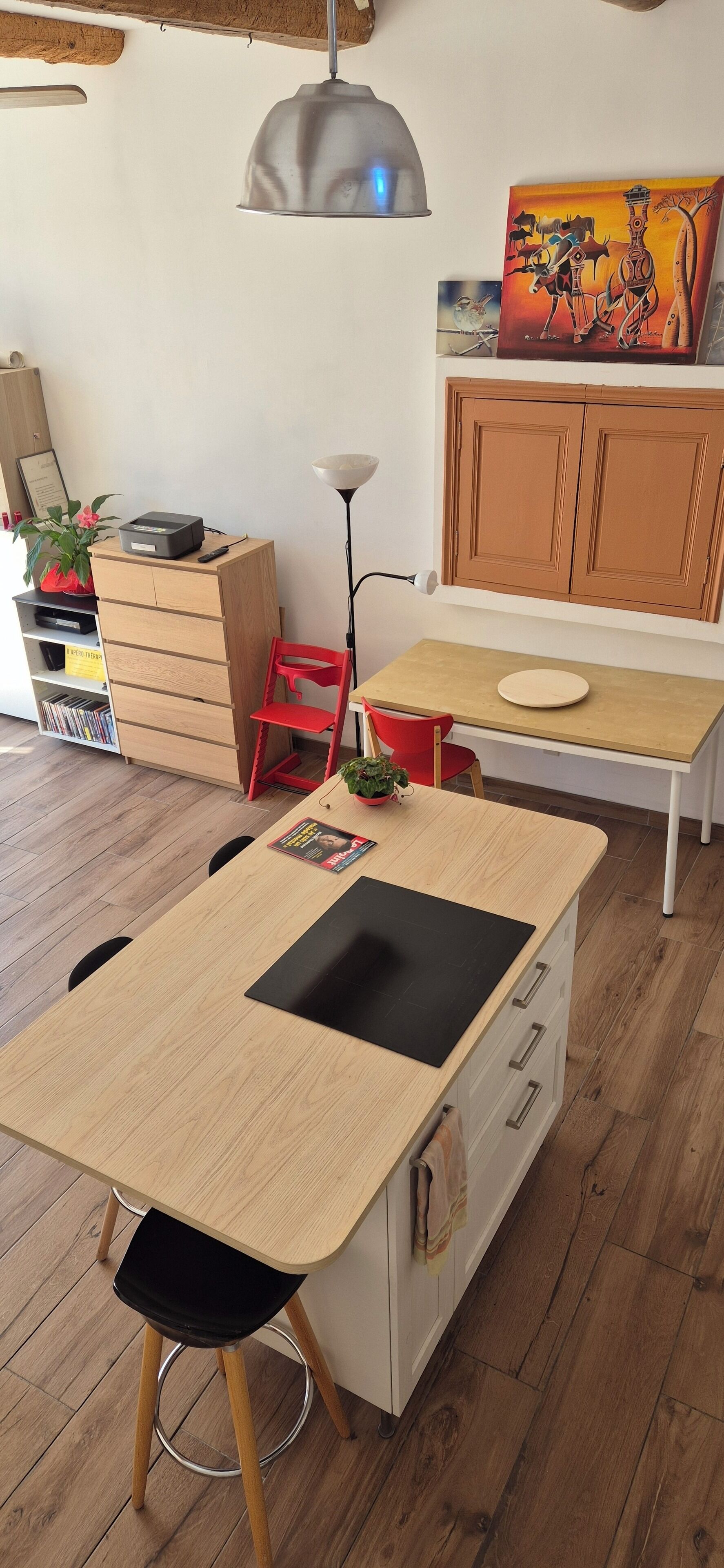 Una cucina moderna con un tavolo in legno, sedie rosse e un armadietto con un quadro sopra.
