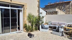 A patio area with a sliding glass door, outdoor furniture, and a dog.
