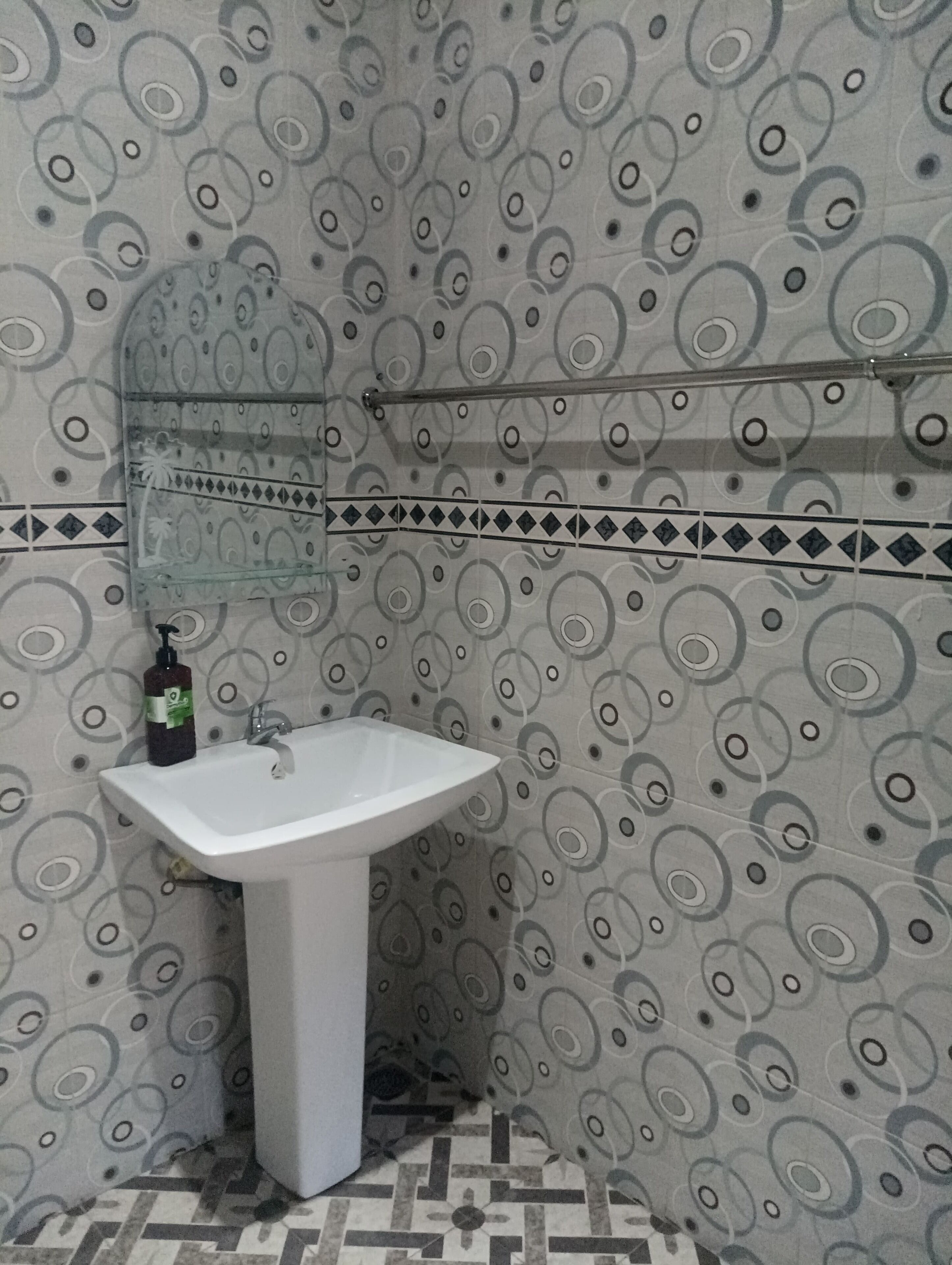 A bathroom with a white sink, a mirror, and patterned walls.