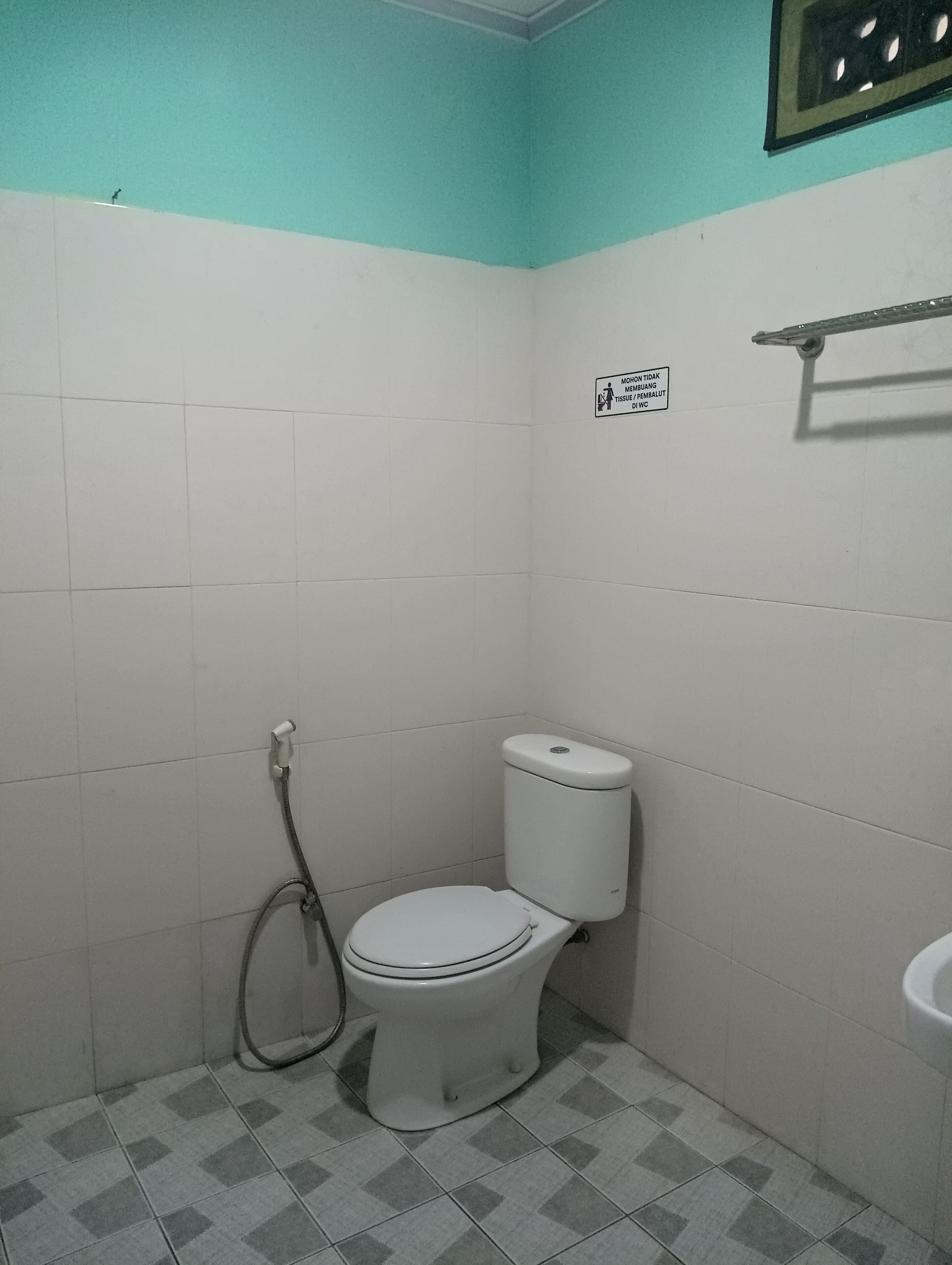 A small, tiled bathroom with a toilet, a shower, and a sink.