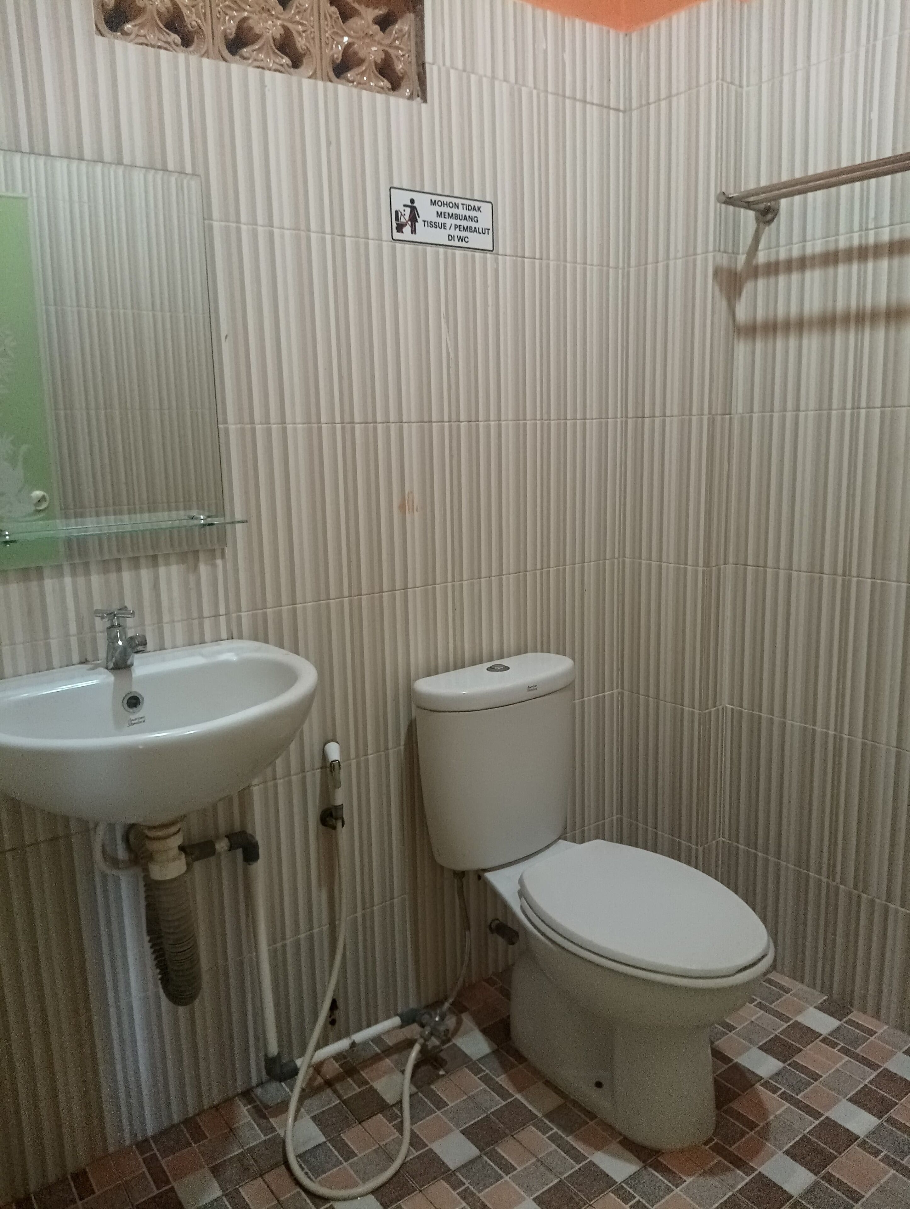 Un baño con lavamanos, inodoro y barra de apoyo.