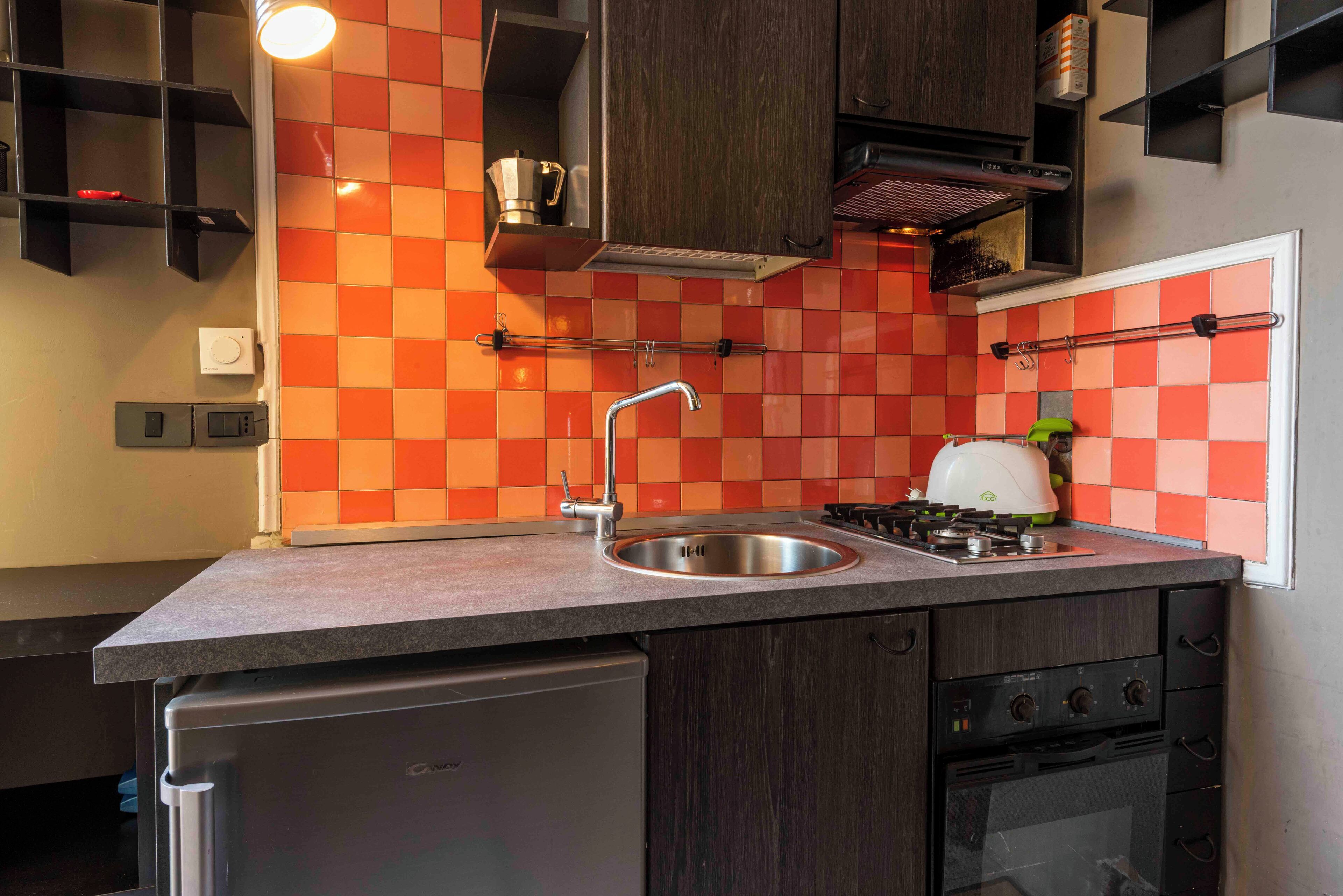 Una cocina con un lavamanos de acero inoxidable, un horno empotrado y una estufa a gas.