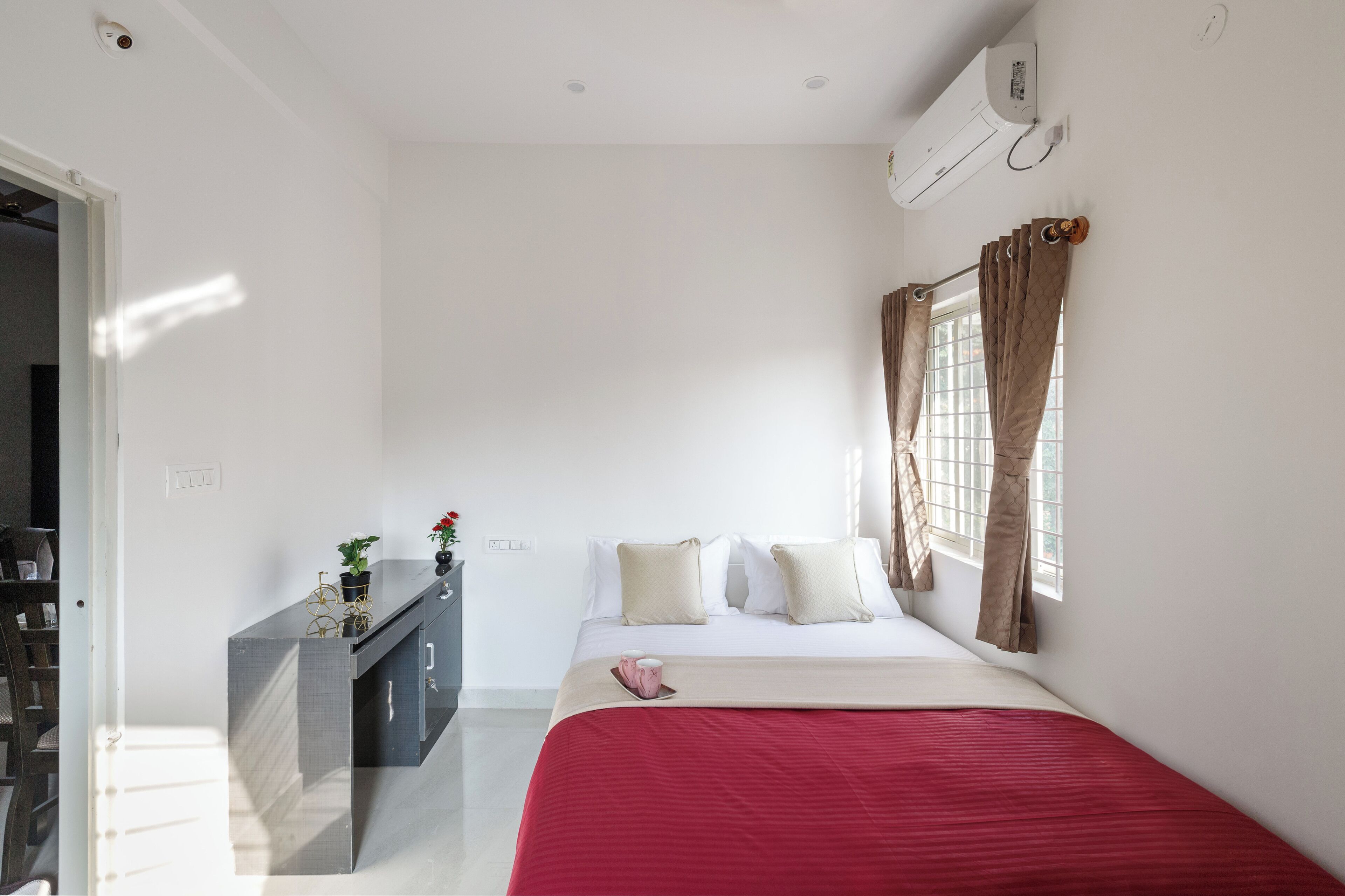 A hotel room with a bed, a desk, and a window with curtains.