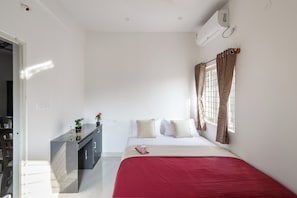 Una habitación de hotel con cama, escritorio y ventana con cortinas.