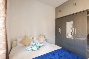 Ein Schlafzimmer mit Bett, Kissen, einer blauen Decke und einem Kleiderschrank.