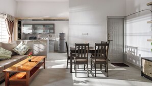 A modern living room with a sofa, coffee table, and dining area with chairs. - The Galleria Home by Red Olive Yelahanka (Bengaluru)