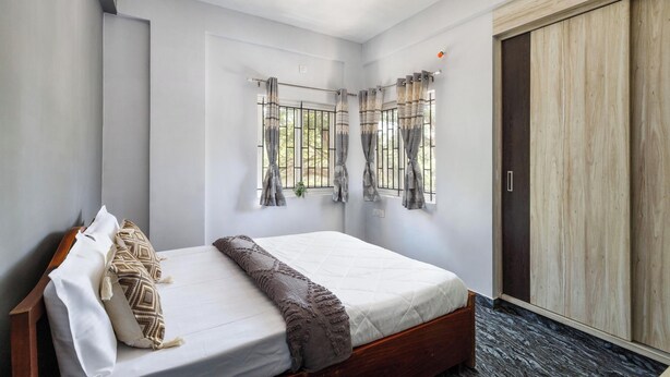 A bedroom with a bed, curtains, a wardrobe, and a window with a view. - The Nebula by Red Olive (Bengaluru)