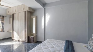 A bedroom with a bed, a wardrobe, a mirror, and a small table. - The Nebula by Red Olive (Bengaluru)
