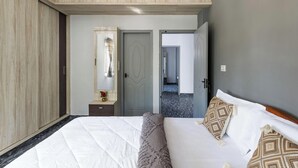 A bedroom with a large bed, a wardrobe, a mirror, and a door leading to another room. - The Nebula by Red Olive (Bengaluru)