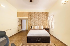 A bedroom with a bed, a chair, a nightstand, and a patterned rug.