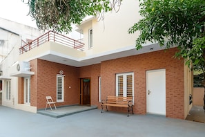 Una casa de dos pisos con un balcón, un banco de madera y una puerta.