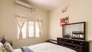 Une chambre à coucher avec un lit, une commode, un miroir et une fenêtre avec des rideaux.