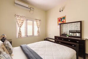 Un dormitorio con cama, cómoda, espejo y ventana con cortinas.