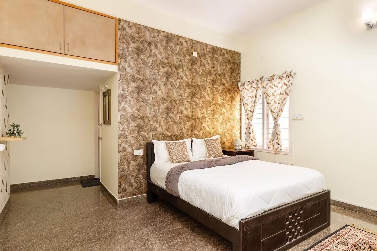 A bedroom with a bed, a wardrobe, a nightstand, and a window with curtains.