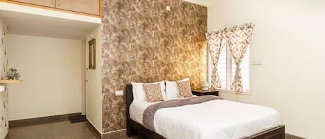 A bedroom with a bed, a wardrobe, a nightstand, and a window with curtains.