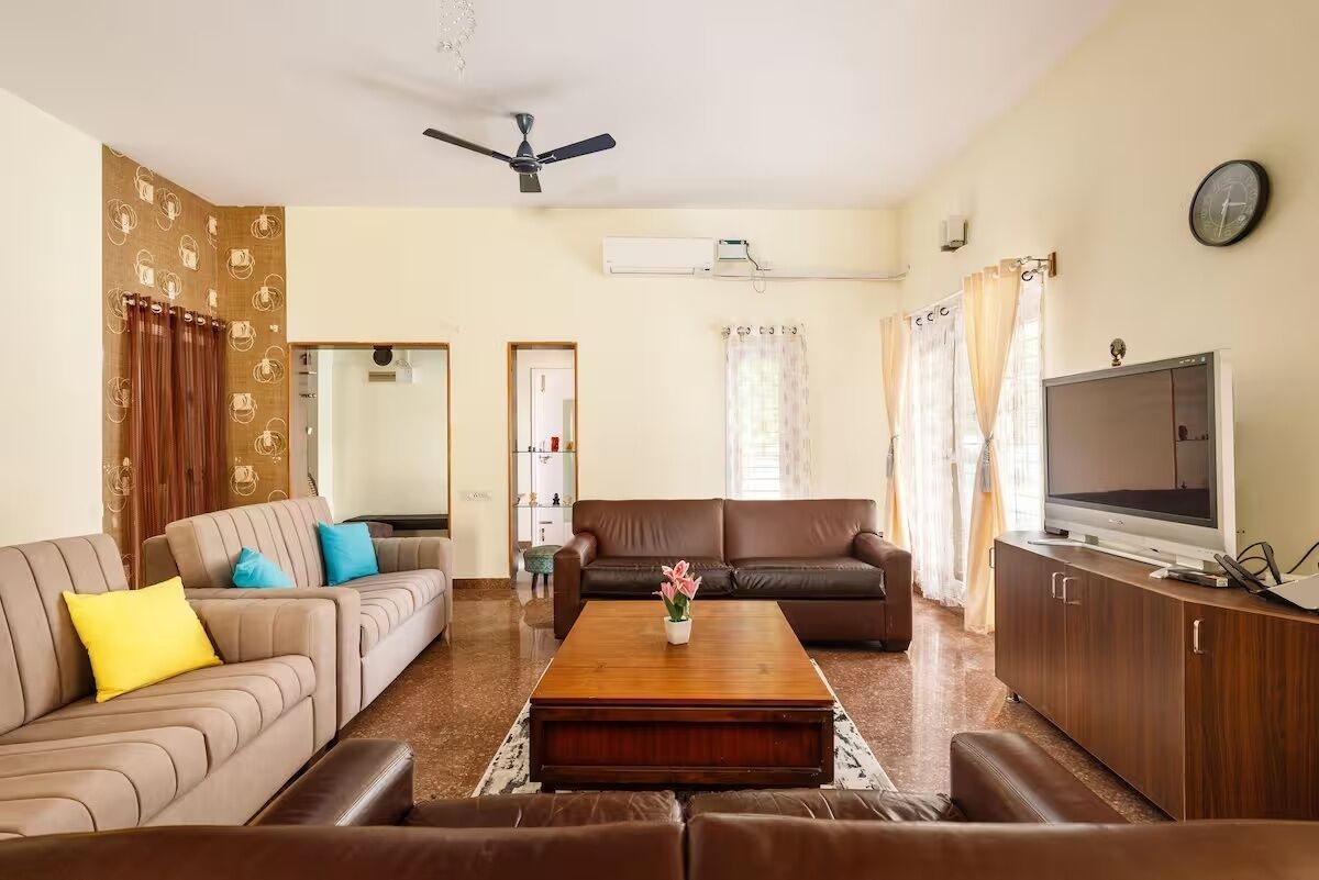 A living room with two sofas, a coffee table, a television, and a ceiling fan.