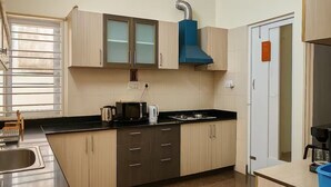 Une cuisine moderne dotée d’un évier en acier inoxydable, d’un plan de travail noir et de meubles en bois.