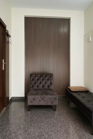 Ein Zimmer mit einer gepolsterten Couch, einer Bank mit gemustertem Kissen und einer Wand mit vertikalem Streifenmuster.
