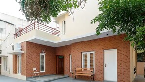 Un immeuble résidentiel de deux étages doté d’un balcon, d’un banc en bois et d’une porte blanche.
