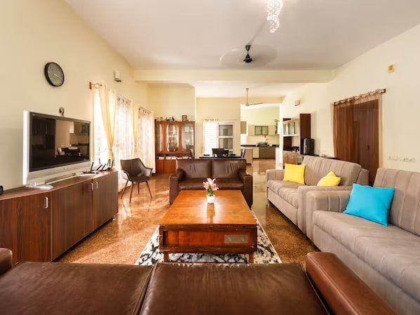 Una sala de estar moderna con televisor de pantalla plana, sofás de cuero, una mesa de centro y un comedor con candelabro.