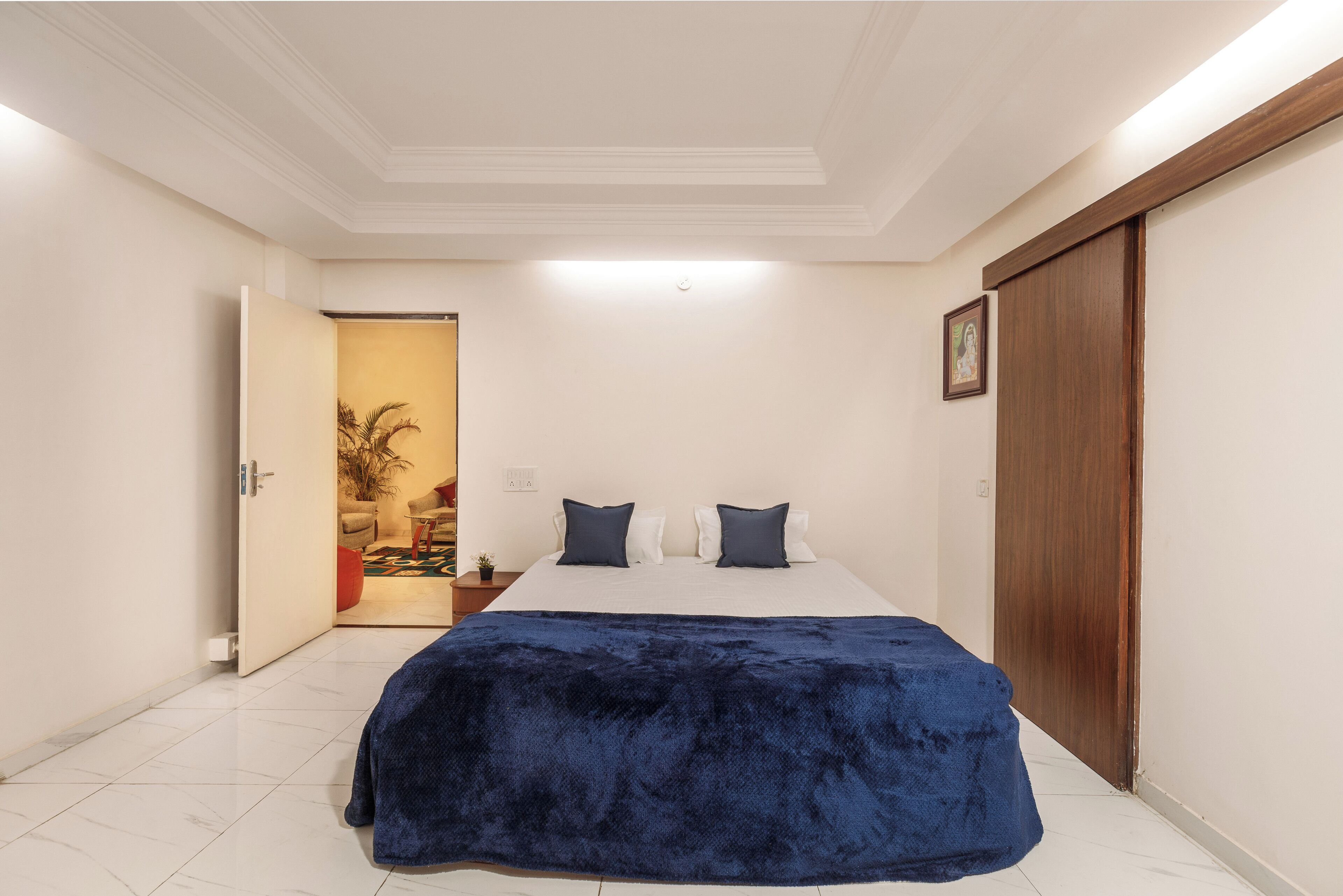 Een slaapkamer met een bed, een houten garderobe en een deur naar een andere kamer.