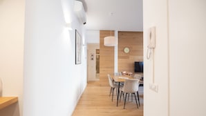 A modern interior with a wooden floor, white walls, and a dining area with a table and chairs. - Barbra Suite Testaccio (Roma)