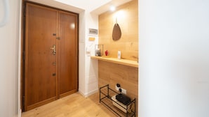 A wooden door, a shelf with a hanging pot, and a small table with a black object. - Barbra Suite Testaccio (Roma)