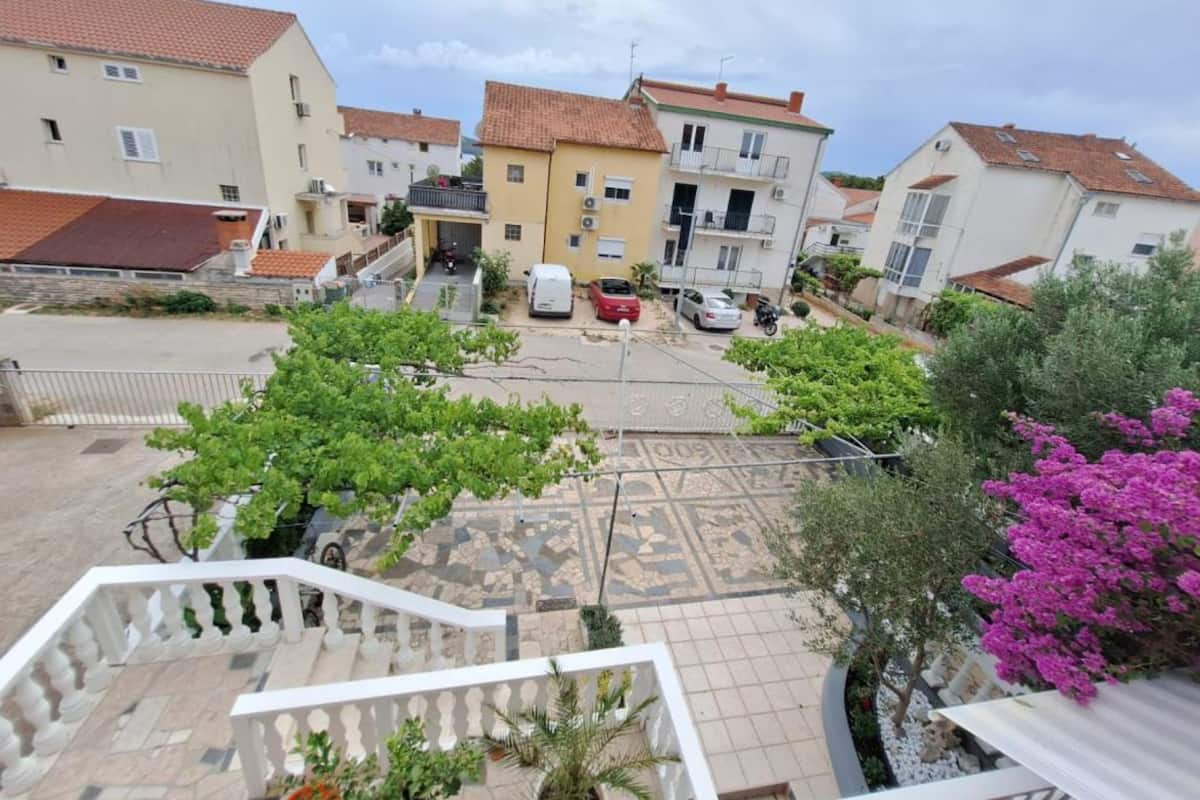 A residential area with a paved courtyard, a staircase, and surrounding houses.