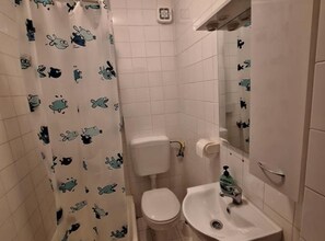 A bathroom with a toilet, sink, and shower curtain with cartoon characters.
