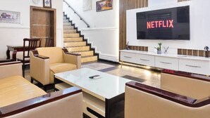 A modern living room with a staircase, a flat-screen TV, and a coffee table. - The Breeze Apartment (Lagos)