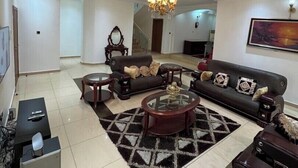 A spacious living room with a large sofa set, a coffee table, and a chandelier. - The Breeze Apartment (Lagos)