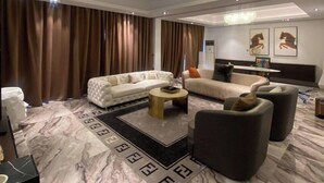 A modern living room with a chandelier, two sofas, a coffee table, and a patterned rug. - The Breeze Apartment (Lagos)