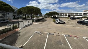 A parking lot with marked spaces, a pedestrian pathway, and a building with a modern design in the background.