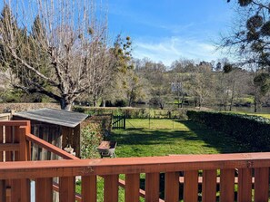 A wooden deck with a view of a well-maintained lawn and a pond.