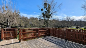 A wooden deck with a railing, overlooking a lake and trees. - Cottage by the Creuse River with Private Garden (Ceaulmont)