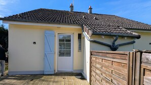 A house with a tiled roof, a wooden deck, and a white door. - Cottage by the Creuse River with Private Garden (Ceaulmont)