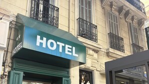 A hotel with a green facade, a signboard, and a potted plant in front. - hôtel du Pharo (Marseille)