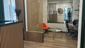 A modern interior with a wooden partition, a round glass table, and an orange chair. - hôtel du Pharo (Marseille)